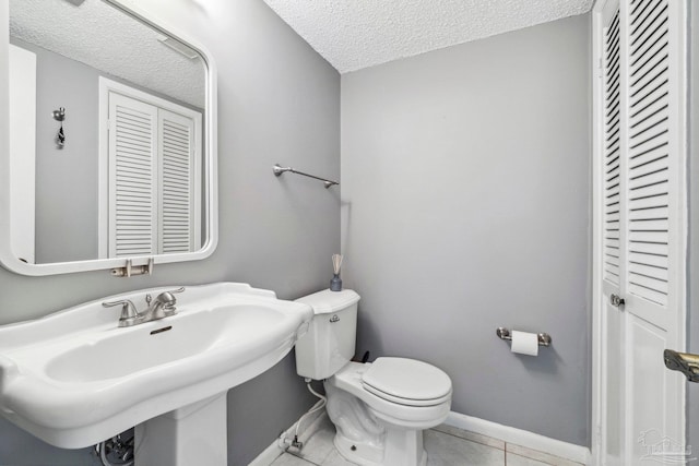 bathroom featuring a textured ceiling, sink, toilet, and tile patterned floors