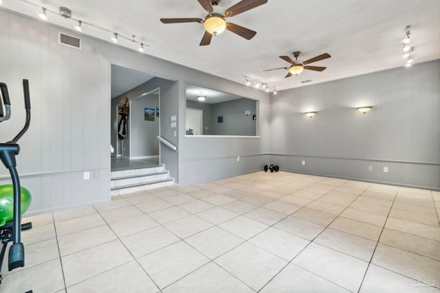 empty room featuring wood walls, ceiling fan, track lighting, and light tile patterned floors