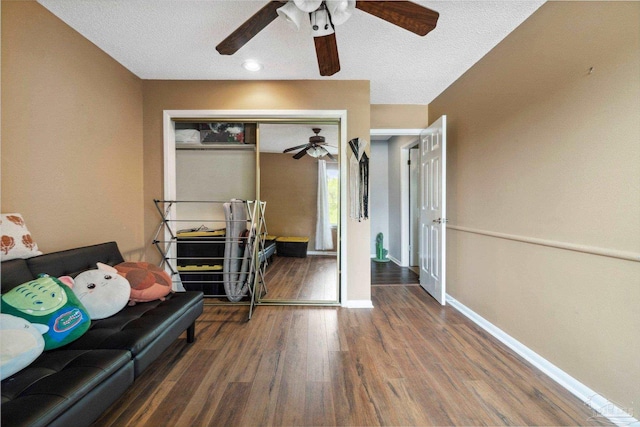 sitting room with ceiling fan, dark wood-type flooring, and a textured ceiling