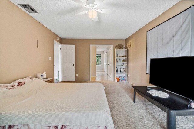 bedroom with ceiling fan, a textured ceiling, and light carpet