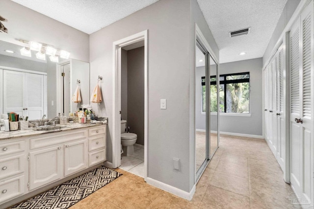 bathroom featuring vanity, toilet, an enclosed shower, a textured ceiling, and tile patterned flooring