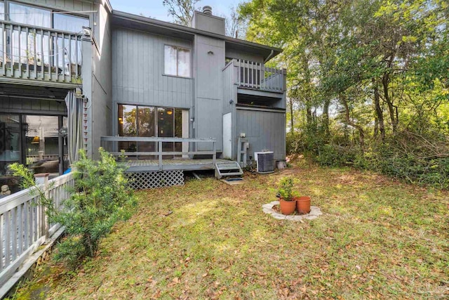 rear view of property with a lawn, a balcony, and central AC unit