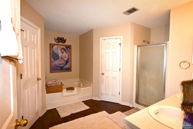 bathroom with vanity, a textured ceiling, hardwood / wood-style flooring, and separate shower and tub