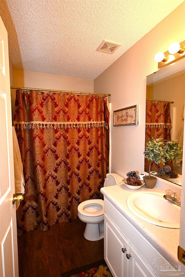 bathroom featuring vanity, hardwood / wood-style floors, toilet, and a textured ceiling