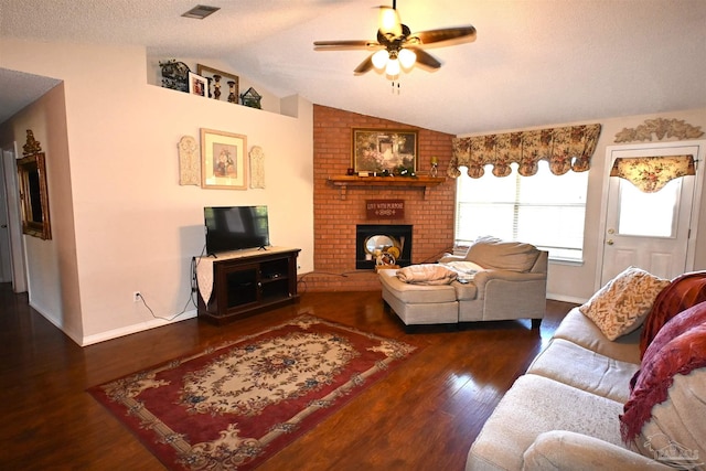 living room featuring dark wood-type flooring, vaulted ceiling, a textured ceiling, a fireplace, and ceiling fan