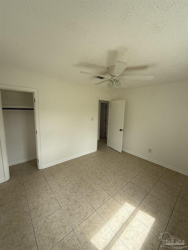 unfurnished bedroom featuring a closet, light tile patterned floors, a textured ceiling, and visible vents