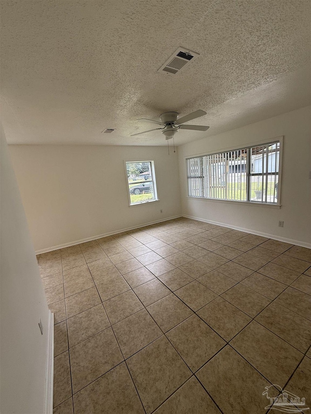 unfurnished room featuring visible vents, baseboards, ceiling fan, tile patterned floors, and a textured ceiling