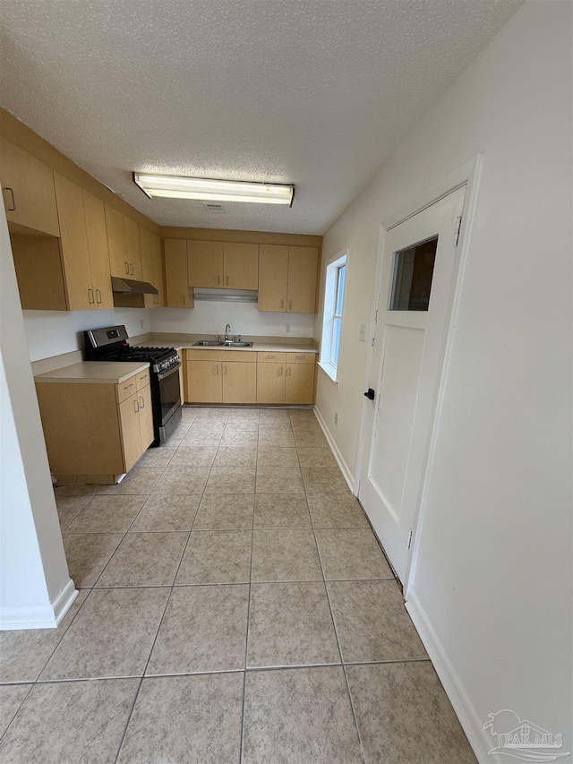 kitchen with a sink, light countertops, light brown cabinetry, and stainless steel gas range oven