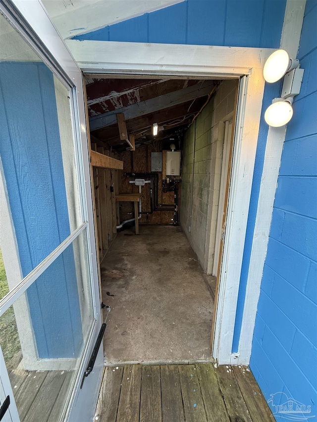 interior space with tankless water heater, concrete block wall, and wood-type flooring