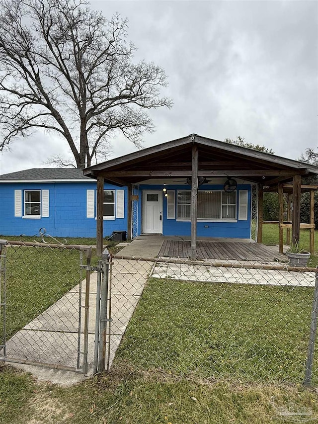 view of front of home with a fenced front yard, concrete block siding, a front lawn, and a gate