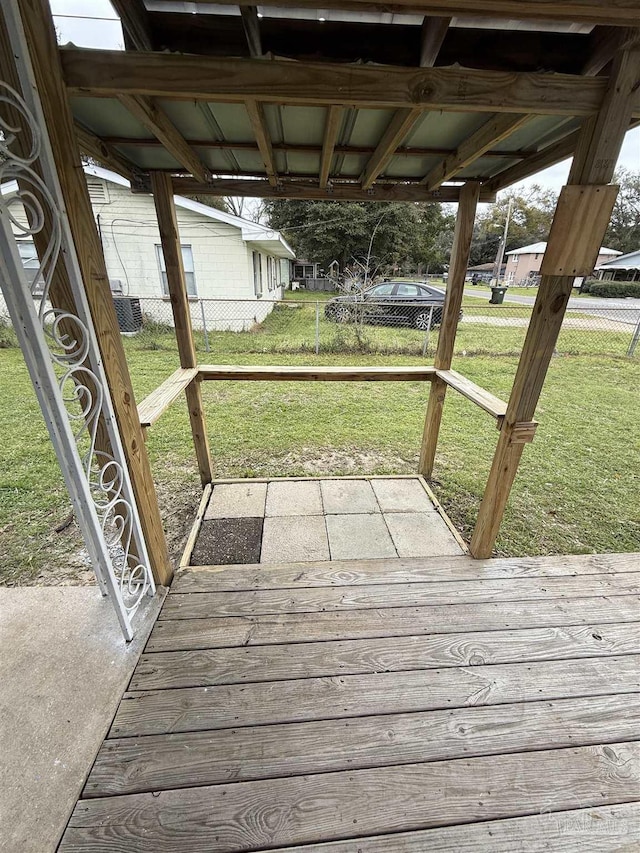 wooden deck with a carport, central air condition unit, a lawn, and fence