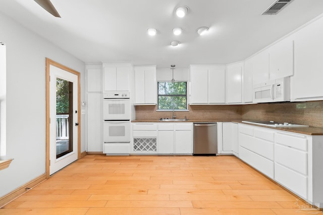 kitchen featuring tasteful backsplash, visible vents, light wood-style flooring, white appliances, and a sink