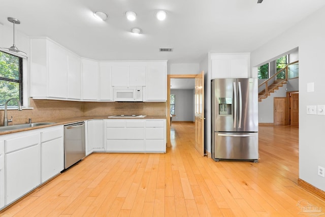 kitchen featuring tasteful backsplash, visible vents, light wood finished floors, stainless steel appliances, and a sink