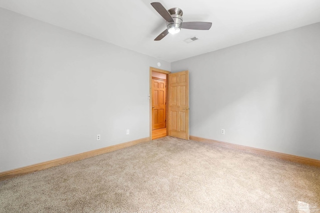 unfurnished room with visible vents, light colored carpet, baseboards, and ceiling fan