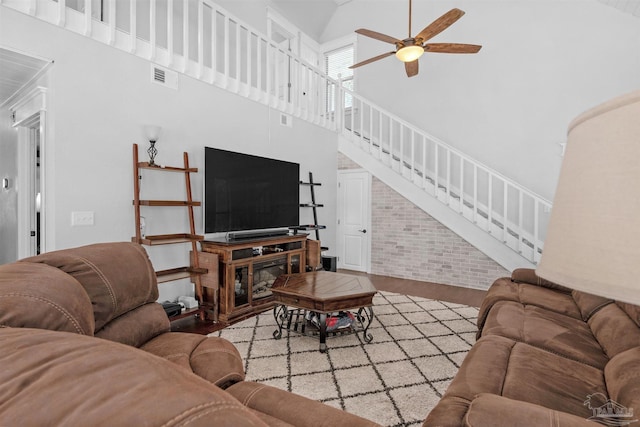 living room with stairs, wood finished floors, ceiling fan, visible vents, and a towering ceiling