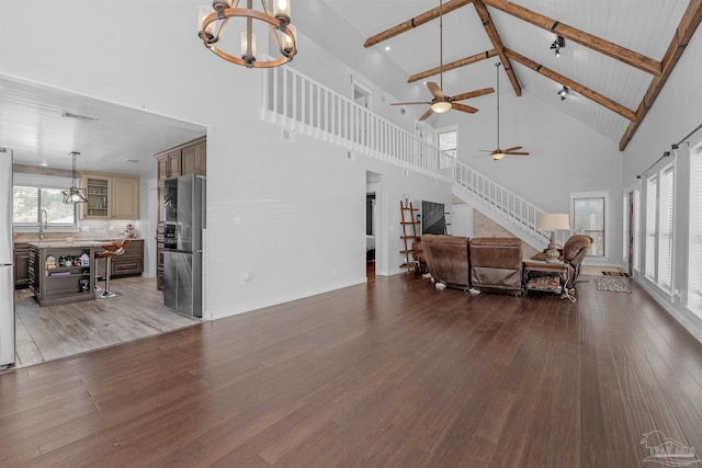living room with stairs, ceiling fan with notable chandelier, beamed ceiling, visible vents, and wood finished floors