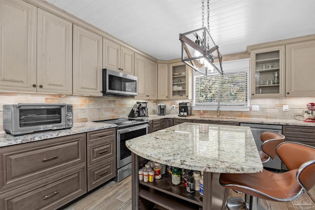 kitchen featuring cream cabinetry, a toaster, stainless steel appliances, a sink, and open shelves