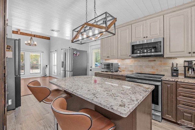 kitchen with a chandelier, a toaster, plenty of natural light, tasteful backsplash, and appliances with stainless steel finishes