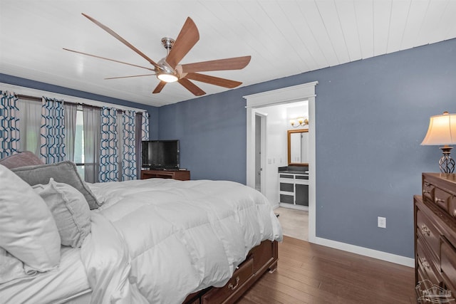 bedroom featuring dark wood finished floors, baseboards, ceiling fan, and ensuite bathroom