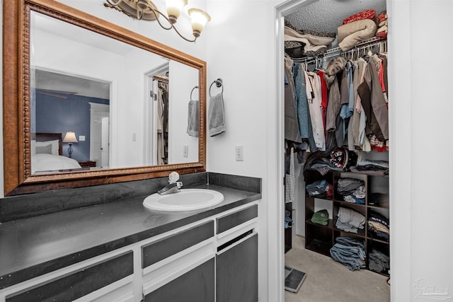 bathroom featuring a spacious closet, vanity, connected bathroom, and concrete flooring