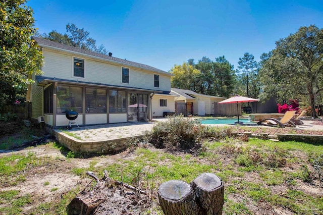 back of property featuring a sunroom, a patio, and an outdoor pool