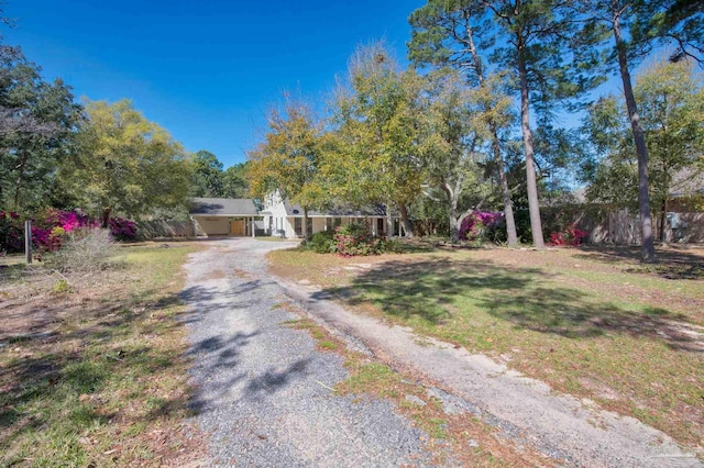 view of front facade featuring a front yard, gravel driveway, and fence