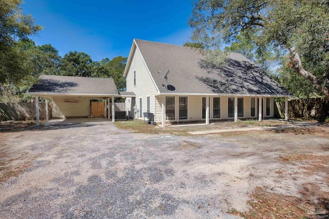 view of front of home with an attached carport, driveway, and fence
