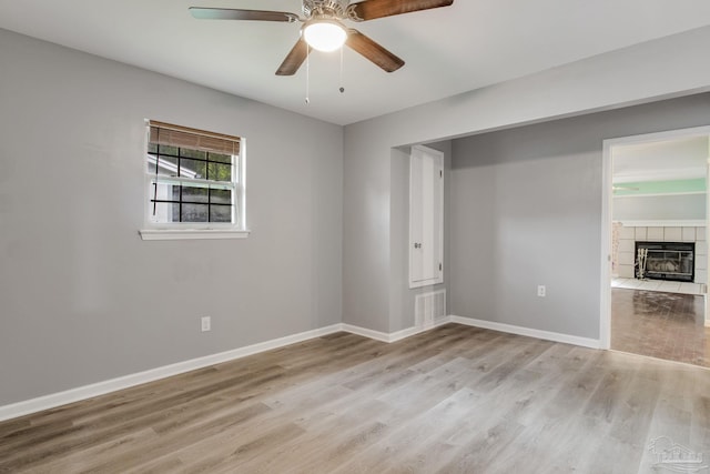 spare room with hardwood / wood-style flooring, a fireplace, and ceiling fan