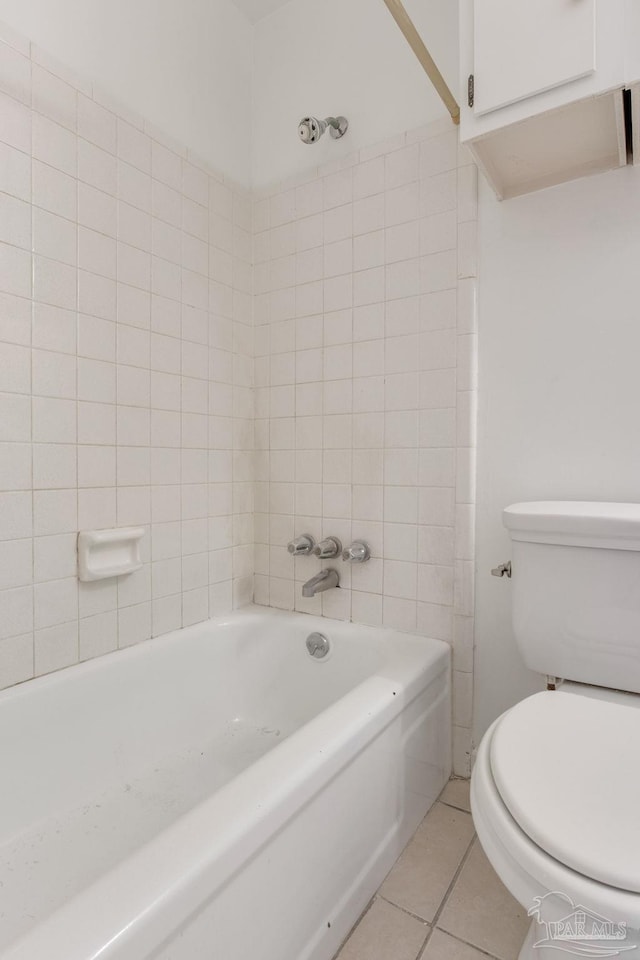 bathroom featuring tile patterned flooring, tiled shower / bath combo, and toilet