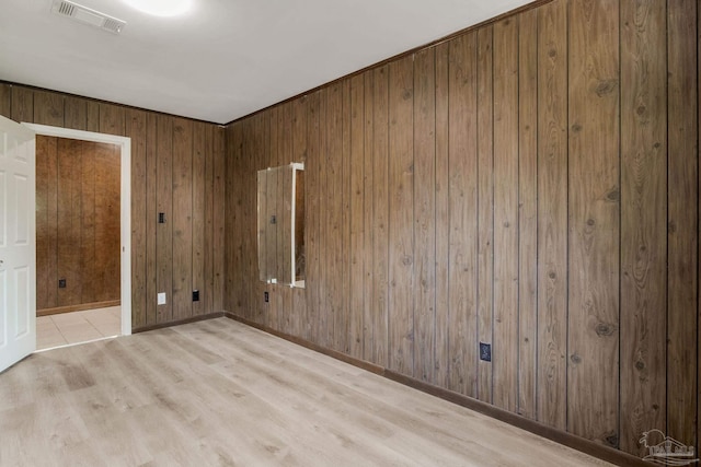 spare room with light hardwood / wood-style flooring and wooden walls