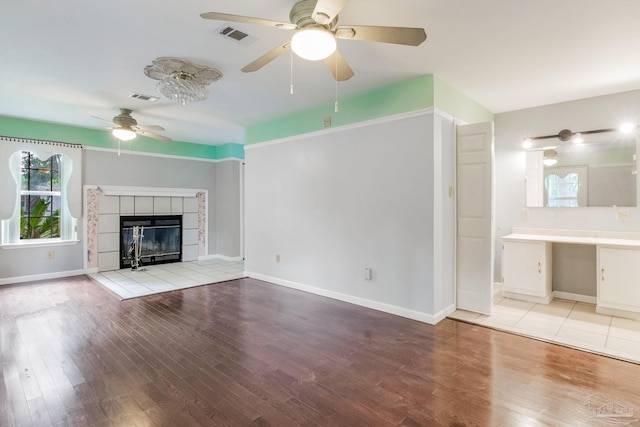 unfurnished living room featuring light wood-type flooring, ceiling fan, and a fireplace