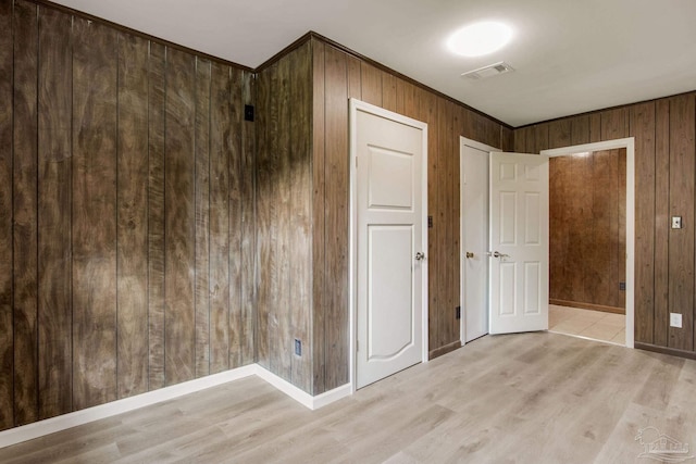 unfurnished bedroom featuring wood walls and light wood-type flooring