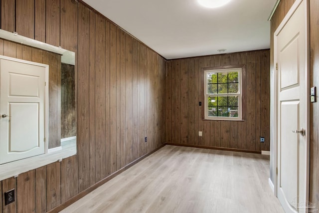 spare room with wood walls and light hardwood / wood-style floors