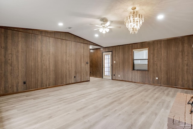 empty room with wood walls, light hardwood / wood-style flooring, lofted ceiling, and ceiling fan with notable chandelier