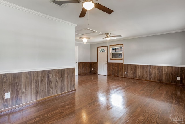 empty room with wood walls, ceiling fan, crown molding, and dark hardwood / wood-style floors