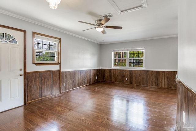 empty room featuring ceiling fan, wood walls, hardwood / wood-style floors, and ornamental molding