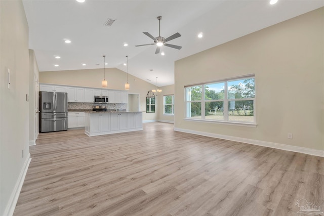 unfurnished living room with ceiling fan with notable chandelier, high vaulted ceiling, and light hardwood / wood-style flooring