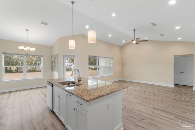 kitchen with light stone counters, sink, white cabinetry, decorative light fixtures, and ceiling fan with notable chandelier