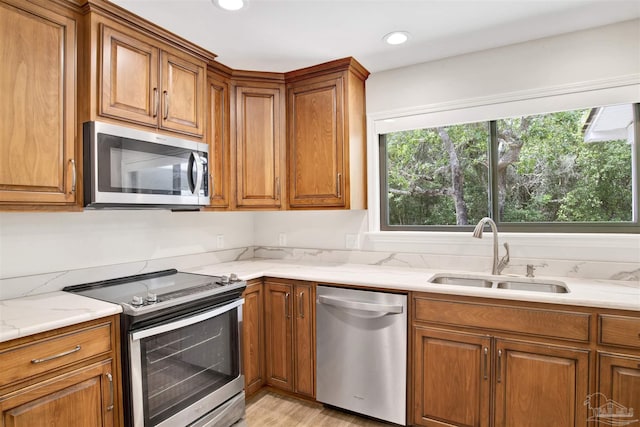 1118 Tall Pine Trl, Gulf Breeze, FL 32561 - kitchen with appliances with stainless steel finishes, a sink, brown cabinetry, light wood-style flooring, and recessed lighting