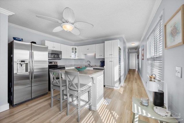 kitchen with white cabinets, crown molding, sink, a textured ceiling, and stainless steel appliances