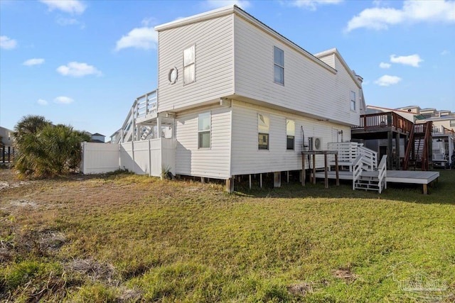 back of house featuring a lawn and a wooden deck