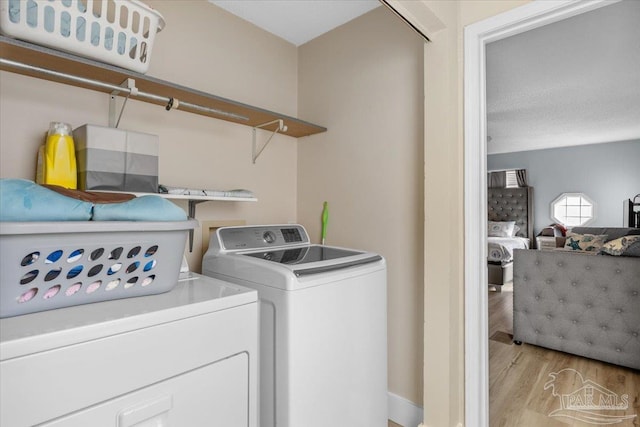 washroom featuring a textured ceiling, light wood-type flooring, and separate washer and dryer