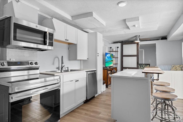 kitchen with white cabinets, a barn door, a breakfast bar area, and appliances with stainless steel finishes