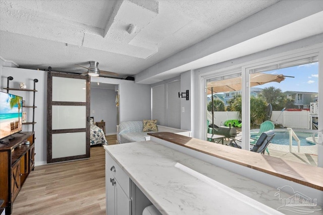 kitchen with a barn door, light stone counters, light hardwood / wood-style floors, and a textured ceiling