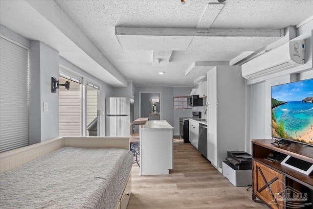 kitchen with a center island, white cabinets, light hardwood / wood-style flooring, a textured ceiling, and stainless steel appliances