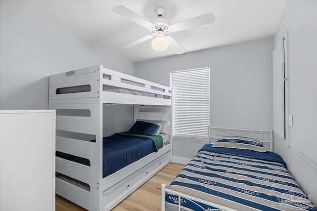 bedroom featuring ceiling fan, hardwood / wood-style floors, and a textured ceiling