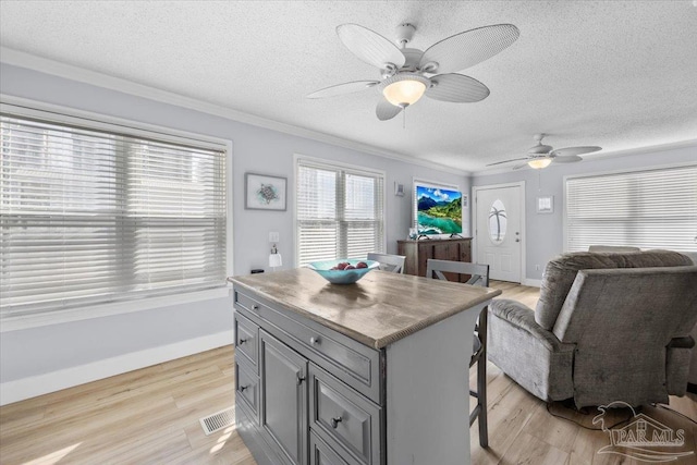 kitchen with a center island, light hardwood / wood-style floors, ceiling fan, and crown molding