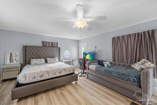 bedroom with ceiling fan, a textured ceiling, and light wood-type flooring