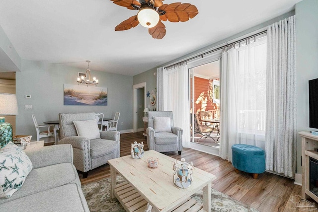 living room with ceiling fan with notable chandelier and hardwood / wood-style flooring