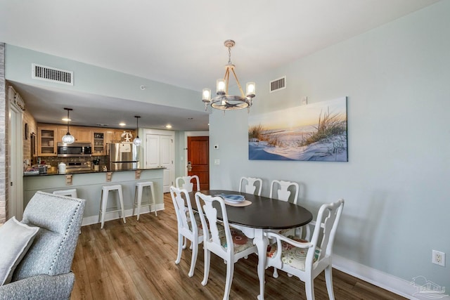 dining area with light hardwood / wood-style floors and an inviting chandelier